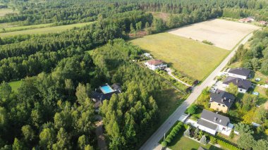 Ormanla çevrili lüks bir evin havadan görünüşü.