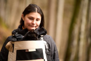 Güzel doğa manzarasında siyah kedisi olan bir kadın.