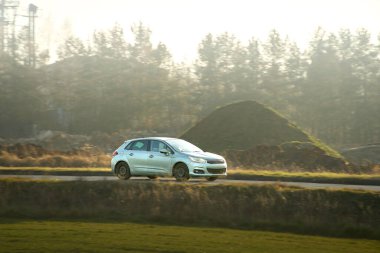 Gümüş renkli modern araba güneşli bir günde hareket ediyor.