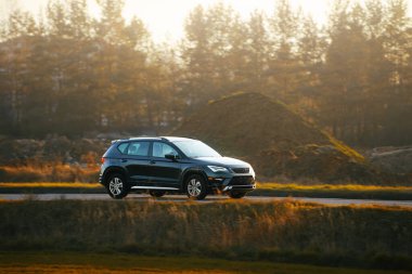 Sonbahar manzarasında alacakaranlıkta gezinen bir SUV.