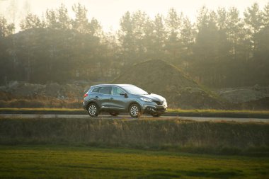 Sonbahar manzarasında alacakaranlıkta gezinen bir SUV.