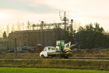 Küçük kazıcı büyük sarı kamyonla taşınıyor.