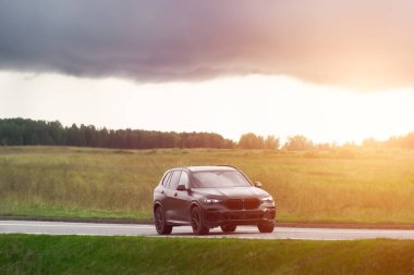 Zarif siyah SUV manzaralı yeşil kırsal alanda sürüyor.