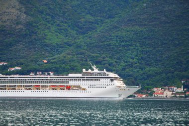 Gün batımında dağlara yakın büyük bir yolcu gemisi.