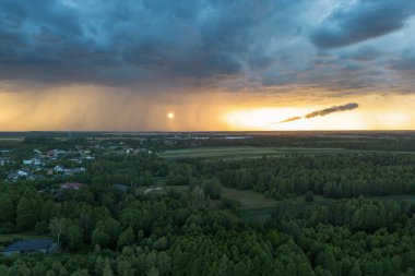 Kara fırtına bulutlarının yaklaştığı kırsal bölgede gün batımı