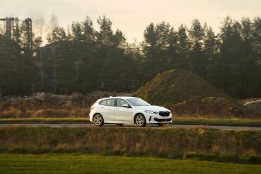 Kırsal bölgede beyaz SUV aracı sürüyor.