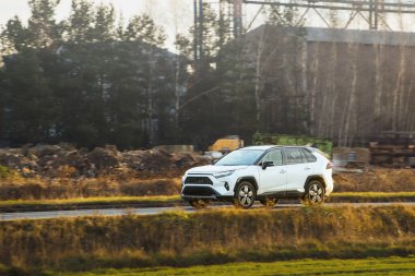 Kırsal alanda dolaşan beyaz elektrikli araba.