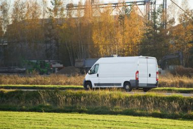 Sonbahar manzarası boyunca giden beyaz minibüs.