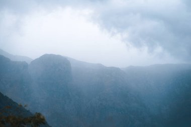 Bulutlu bir günde, sis dağların üzerinde yuvarlanıyor.