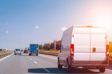 Otoyolda beyaz minibüs sürüyor.