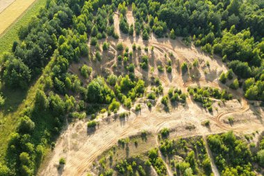 Yukardan görülen bir ormanın içinde dönen moto motorsiklet izleri