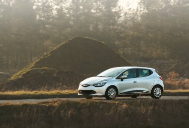 Küçük bir hatchback huzurlu kırsaldan geçiyor.