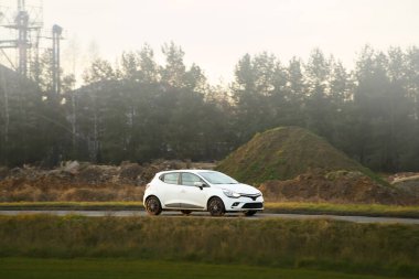 Beyaz Hatchback güneşli kır yolunda hareket halinde.