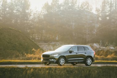 Gün batımında kırsal yolda SUV var.