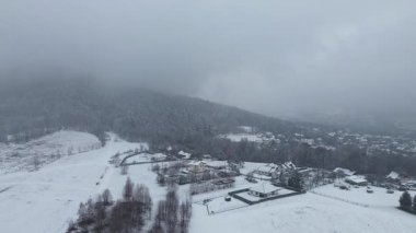 Sisli tepeleri ve ağaçları olan donmuş bir manzara.