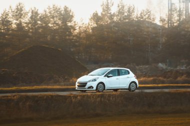 Huzurlu kırsal yolda ilerleyen kompakt araba