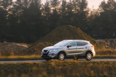 Gün batımında kırsal alanda gezinen arazi aracı.