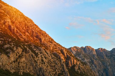 Mavi gökyüzüne uzanan vahşi dağlar.