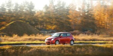 Kırsal yolda giden küçük bir hatchback arabası.