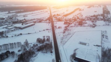 Karlı kırsalda, alacakaranlıkta bir karayolu ile