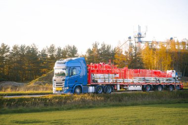 Mavi kargo kamyonu inşaat malzemeleri taşıyor.