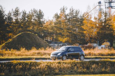 Kırsal yolda ilerleyen kompakt araba