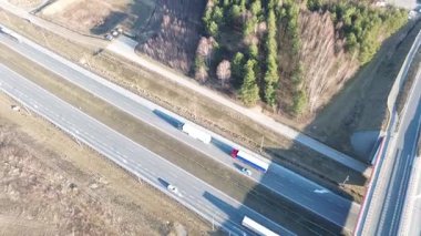 Kırsal alanda otoyolda giden beyaz bir kamyon.