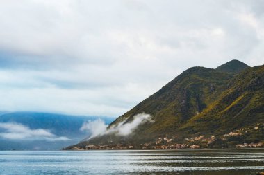 Bulutlu bir sabahta puslu dağlar ve göl