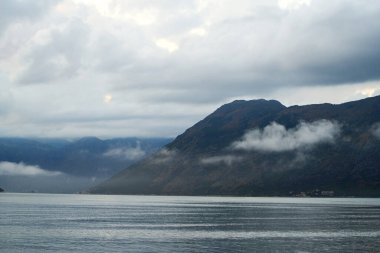 Bulutlu bir sabahta puslu dağlar ve göl