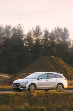 Beyaz araba kırsaldan geçiyor.