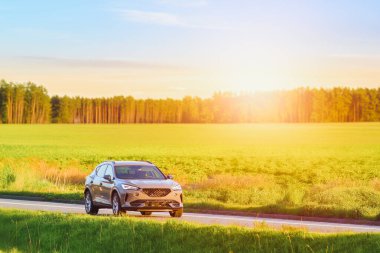 Günbatımında modern SUV manzaralı kırsal bölgelerden geçiyor.