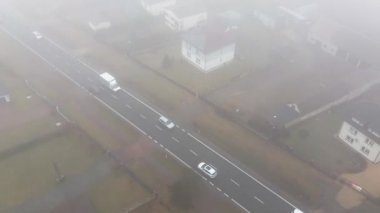 Araba sisli otoban manzarası boyunca gidiyor.