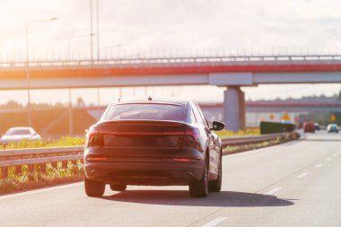 Güneşli bir günde siyah araba sürüyor.