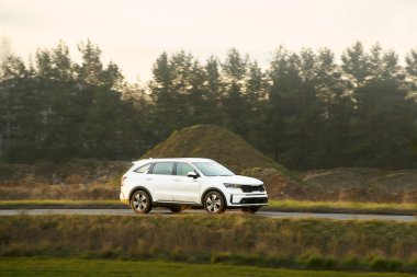 Kırsal alanda beyaz lüks SUV sürüyor.