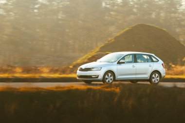 Küçük bir hatchback huzurlu kırsaldan geçiyor.