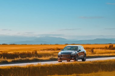 Yaz akşamı kırsal yolda siyah lüks bir SUV.