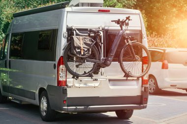 Arka rafında bisikleti olan gümüş renkli bir karavan.
