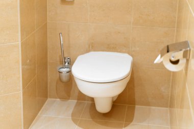 Kapalı tuvalet kapağı olan minimalist bir banyo.