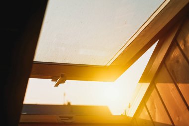 Açık, nemli bir çatı penceresinden gün doğumu ışığı