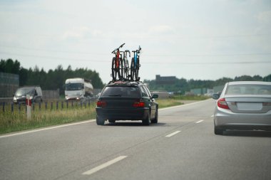 Yolda bisiklet taşıyan bir arabanın olduğu bir trafik sahnesi.