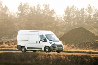 Kırsal kaldırımlı yolda giden lojistik minibüsü