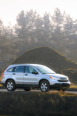 Gün batımında kırsal yolda bir cip hareket halinde.