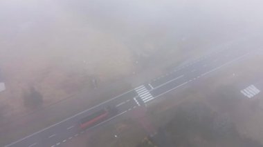 Araba sisli otoban manzarası boyunca gidiyor.