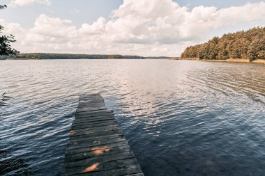 Sessiz suyun üzerine uzanan eski ahşap iskele.