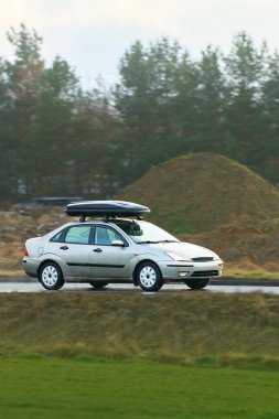 Çatıdaki bagaj kutulu nakliye aracı hareket halinde.