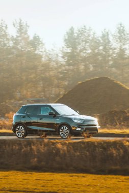 Sonbahar renkleriyle orman yakınlarında seyahat eden bir SUV.