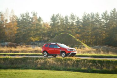 Gün batımında orman yakınlarında arazi aracı sürüyor.