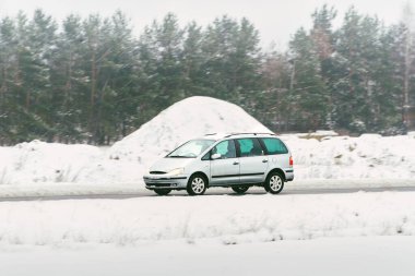 Minibüs kışın karlı yolda gidiyor.