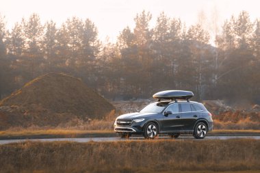 Çatı depolama kutusu olan araba doğada seyahat ediyor.