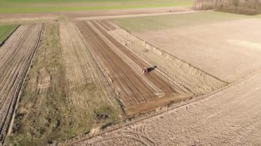 Kırmızı traktörle çalışan geniş tarım arazisi
